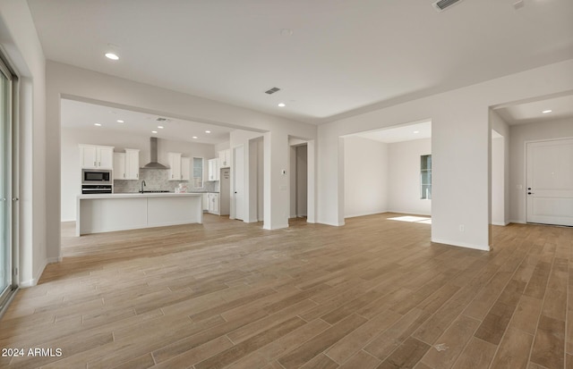 unfurnished living room featuring light hardwood / wood-style flooring and sink