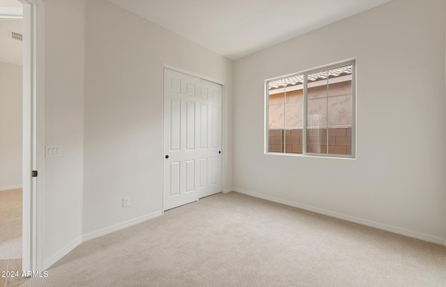 unfurnished bedroom with a closet and light colored carpet