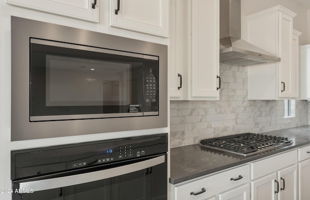 kitchen with wall oven, backsplash, wall chimney exhaust hood, built in microwave, and white cabinetry