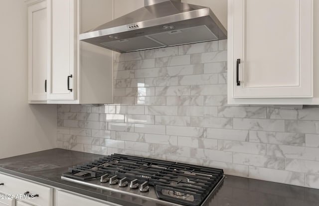 kitchen with decorative backsplash, white cabinets, range hood, and stainless steel gas cooktop