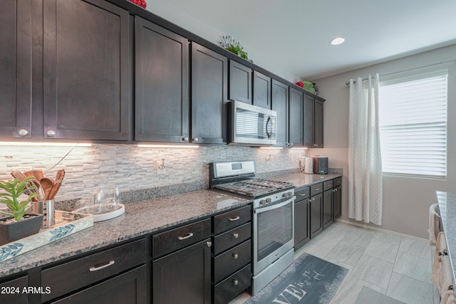 kitchen featuring backsplash, stainless steel appliances, light stone counters, and dark brown cabinetry