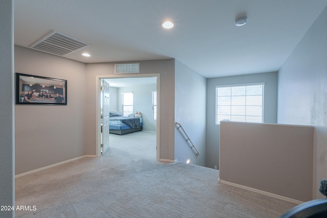 hall with light colored carpet and a healthy amount of sunlight