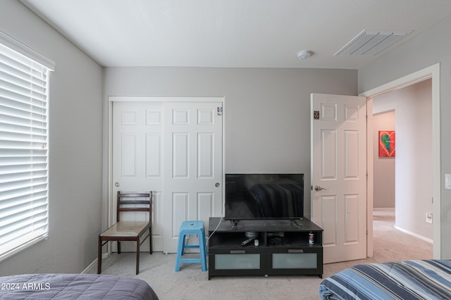 bedroom with a closet, light colored carpet, and multiple windows