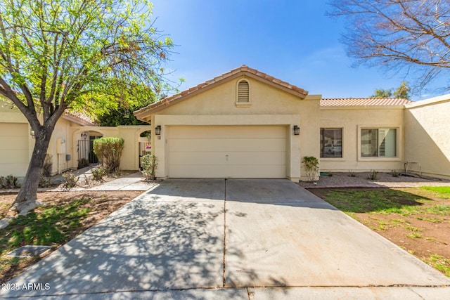 mediterranean / spanish house featuring a tile roof, an attached garage, driveway, and stucco siding