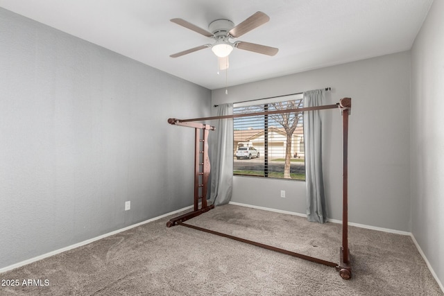 carpeted empty room featuring a ceiling fan and baseboards