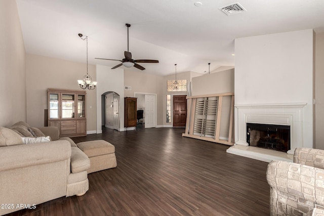 living room with visible vents, high vaulted ceiling, a fireplace with raised hearth, ceiling fan, and dark wood-style flooring