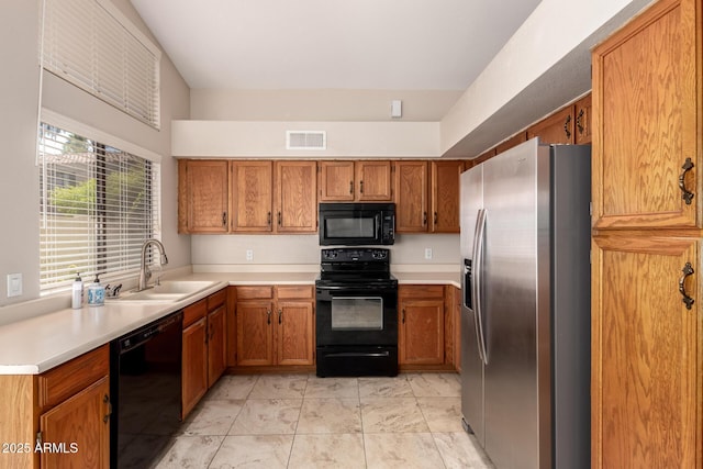 kitchen with visible vents, light countertops, brown cabinetry, black appliances, and a sink