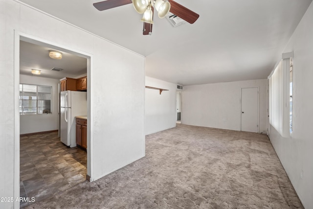 unfurnished living room with dark colored carpet and ceiling fan