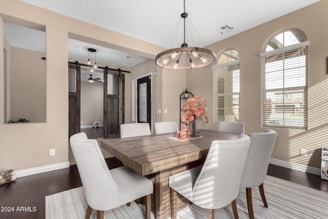 dining space featuring a barn door, dark hardwood / wood-style flooring, and an inviting chandelier