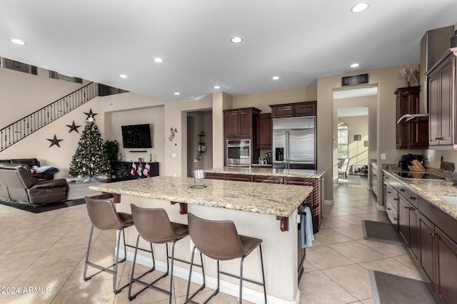 kitchen featuring a breakfast bar, a kitchen island, light stone counters, and stainless steel appliances