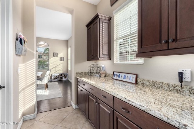 kitchen featuring dark brown cabinetry, light stone counters, and light hardwood / wood-style flooring