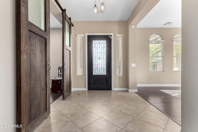 entrance foyer featuring a barn door, an inviting chandelier, and light hardwood / wood-style flooring