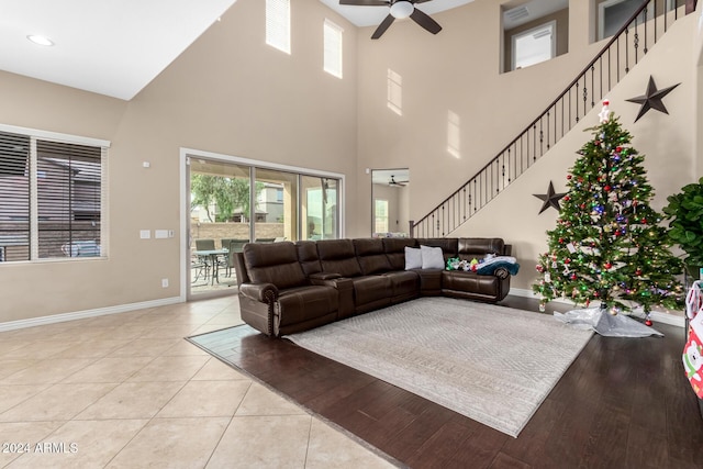 living room with ceiling fan, a towering ceiling, and light tile patterned flooring