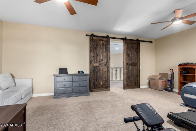 exercise area featuring a barn door, light colored carpet, and ceiling fan