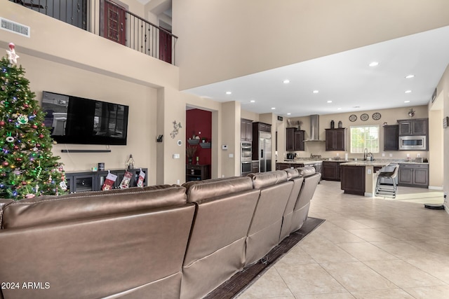 living room with light tile patterned flooring, a towering ceiling, and sink