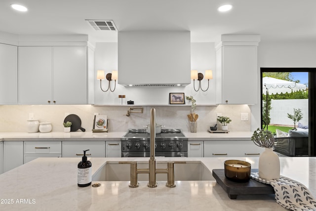 kitchen featuring recessed lighting, visible vents, white cabinetry, backsplash, and range