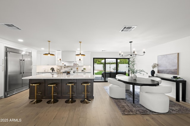 kitchen with light countertops, visible vents, light wood finished floors, and built in refrigerator