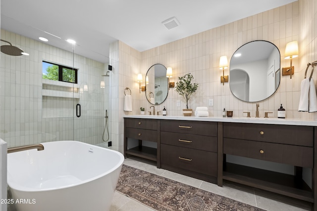 full bath with tile walls, double vanity, visible vents, a stall shower, and a freestanding tub