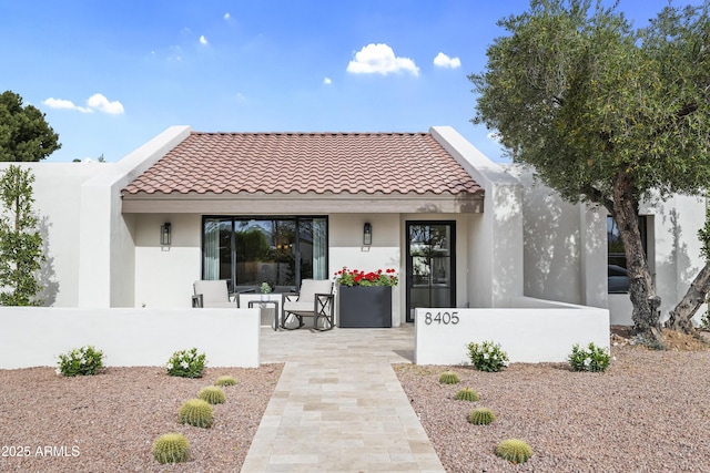 back of property featuring covered porch, a tile roof, and stucco siding