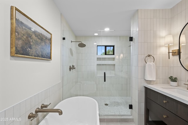 bathroom featuring a stall shower, a freestanding tub, tile walls, and vanity