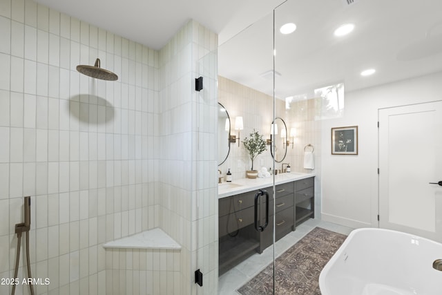 full bath with double vanity, a sink, a tile shower, a freestanding tub, and tile walls