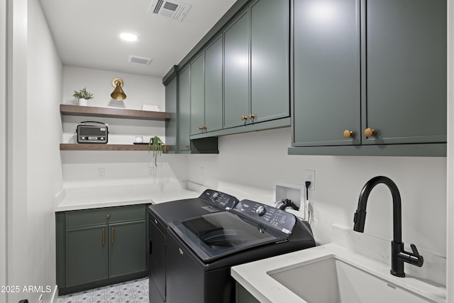 washroom featuring cabinet space, a sink, visible vents, and separate washer and dryer