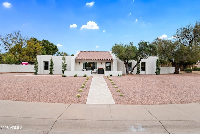 view of front of home with stucco siding, fence, and a tiled roof