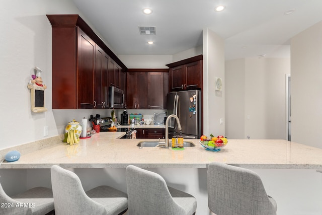 kitchen with a breakfast bar area, stainless steel appliances, sink, and kitchen peninsula