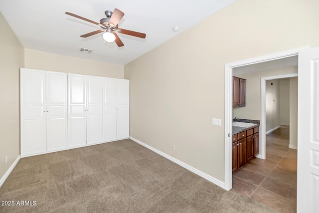 unfurnished bedroom featuring visible vents, baseboards, ceiling fan, and light colored carpet