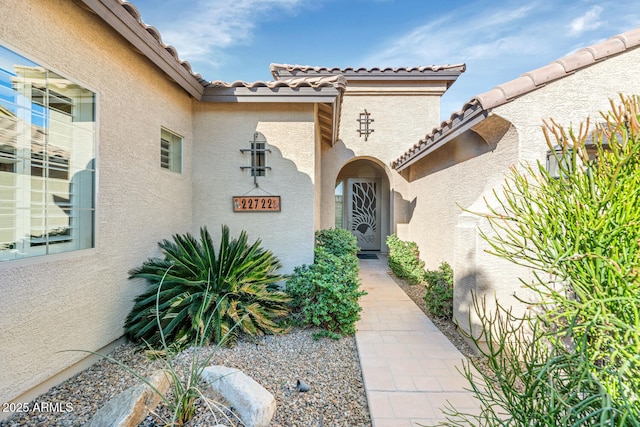 view of exterior entry featuring a tile roof and stucco siding