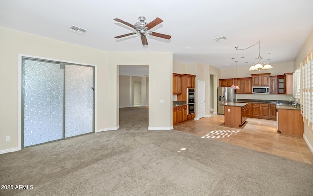 kitchen featuring hanging light fixtures, appliances with stainless steel finishes, brown cabinets, and a center island