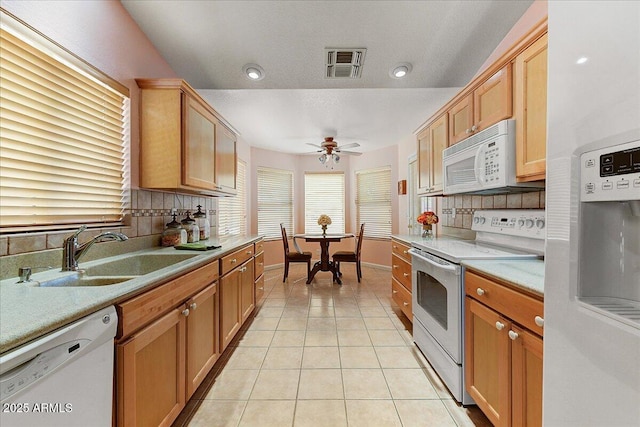 kitchen with light tile patterned flooring, white appliances, sink, and backsplash