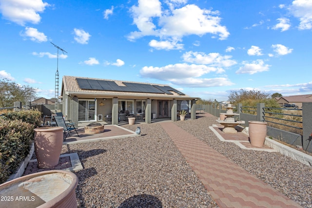 back of house with a fire pit, a patio area, and solar panels