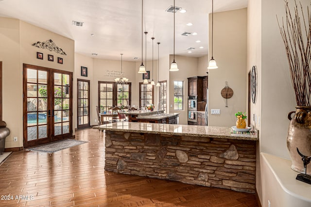 kitchen featuring pendant lighting, a kitchen island, hardwood / wood-style floors, french doors, and light stone countertops