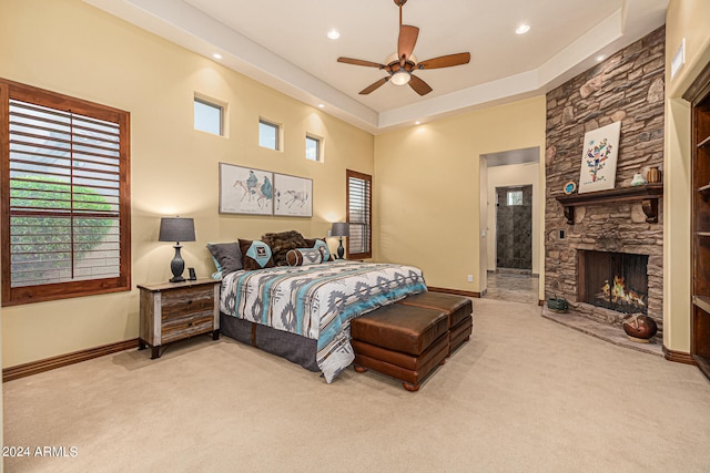 carpeted bedroom featuring ceiling fan, connected bathroom, and a stone fireplace