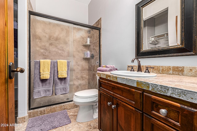 bathroom with tile patterned flooring, a shower with shower door, vanity, and toilet