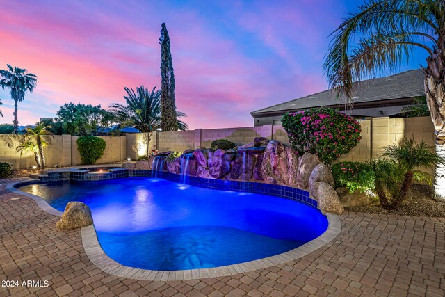 pool at dusk with an in ground hot tub and pool water feature