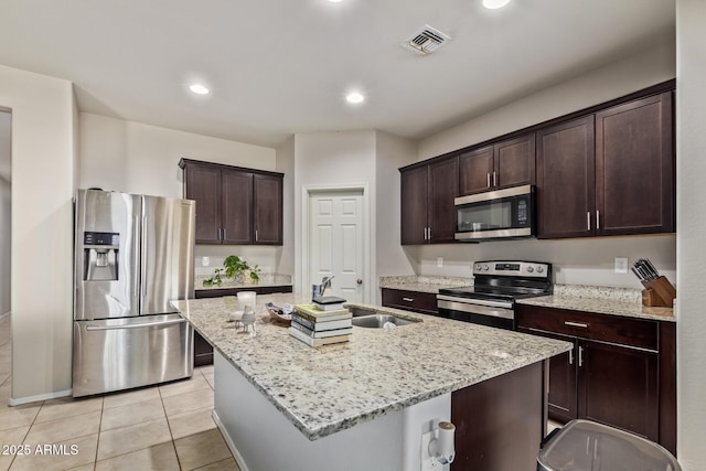 kitchen featuring a kitchen island with sink, dark brown cabinets, visible vents, and stainless steel appliances