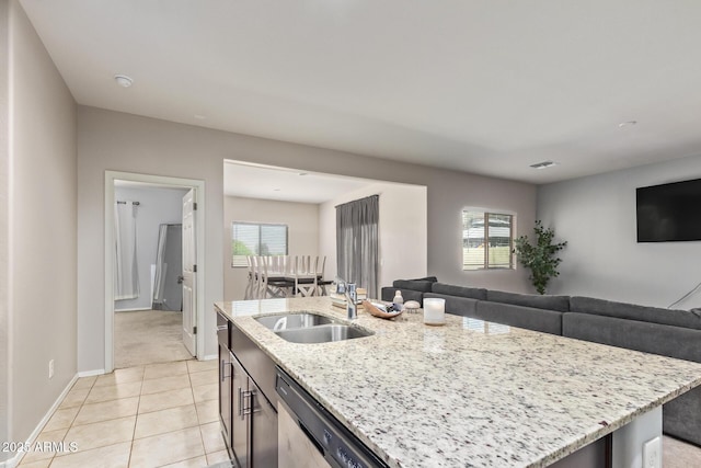 kitchen featuring stainless steel dishwasher, open floor plan, a sink, and light tile patterned floors