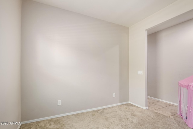 unfurnished room with baseboards, light colored carpet, and light tile patterned flooring