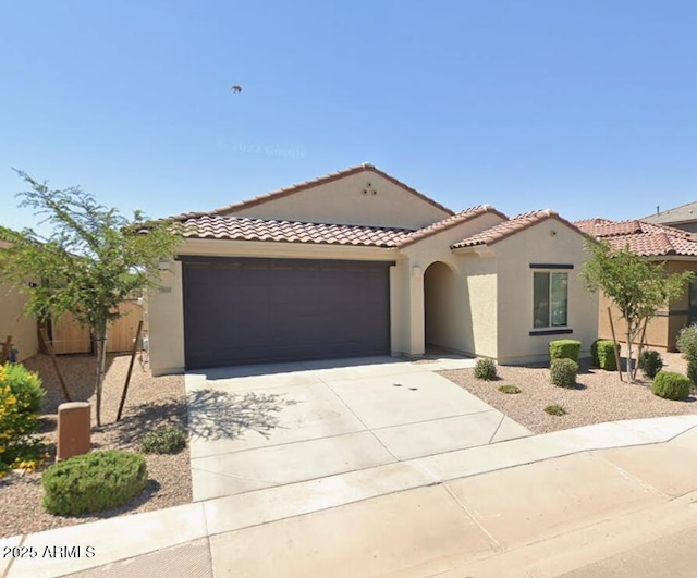 mediterranean / spanish-style home featuring a garage, stucco siding, driveway, and a tile roof