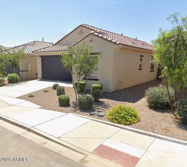 mediterranean / spanish house featuring driveway, stucco siding, a tile roof, and a garage