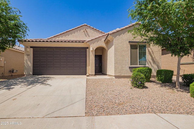 mediterranean / spanish-style home featuring a garage, stucco siding, concrete driveway, and a tile roof