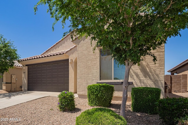 view of front facade with driveway, stucco siding, an attached garage, and a tile roof