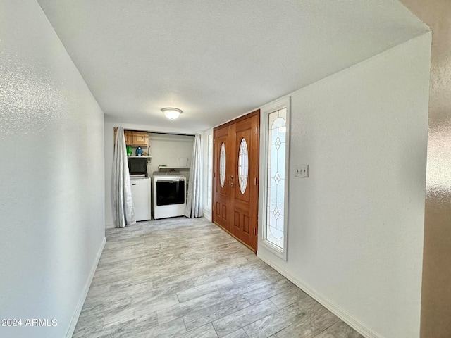 entrance foyer featuring washer and clothes dryer, light hardwood / wood-style flooring, and plenty of natural light