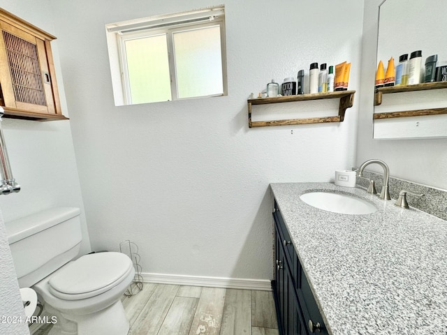 bathroom featuring wood-type flooring, vanity, and toilet