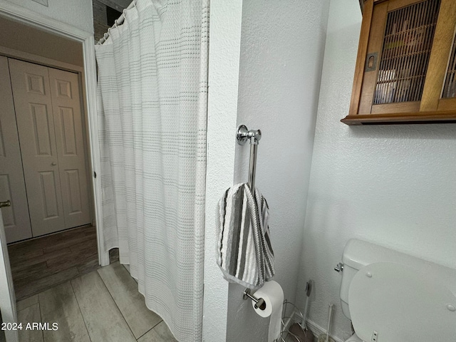 bathroom featuring toilet, a shower with shower curtain, and hardwood / wood-style flooring