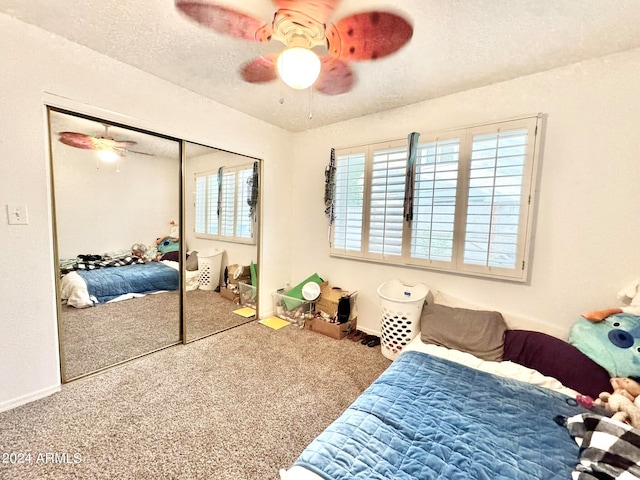 carpeted bedroom with ceiling fan, a textured ceiling, a closet, and multiple windows