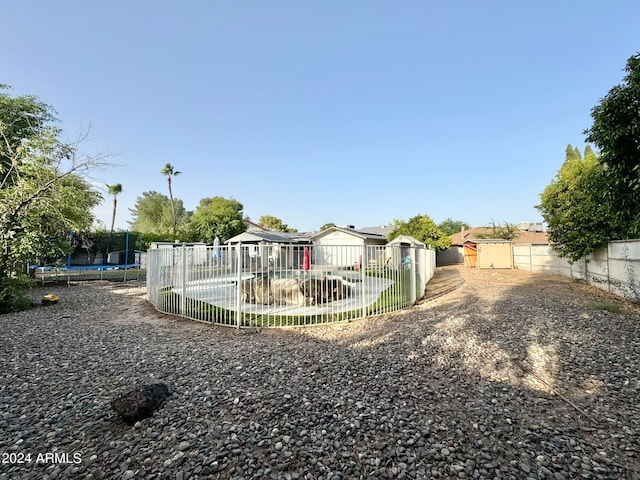 view of yard featuring a trampoline, a fenced in pool, and a patio area