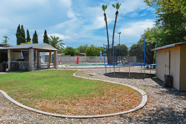 view of yard with a trampoline, an outdoor structure, and a fenced in pool